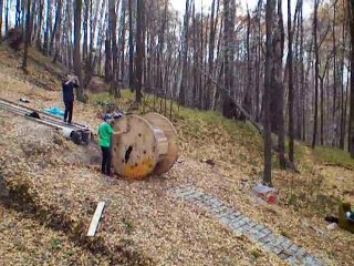 2 russes dévalent une pente dans une bobine géante de cable