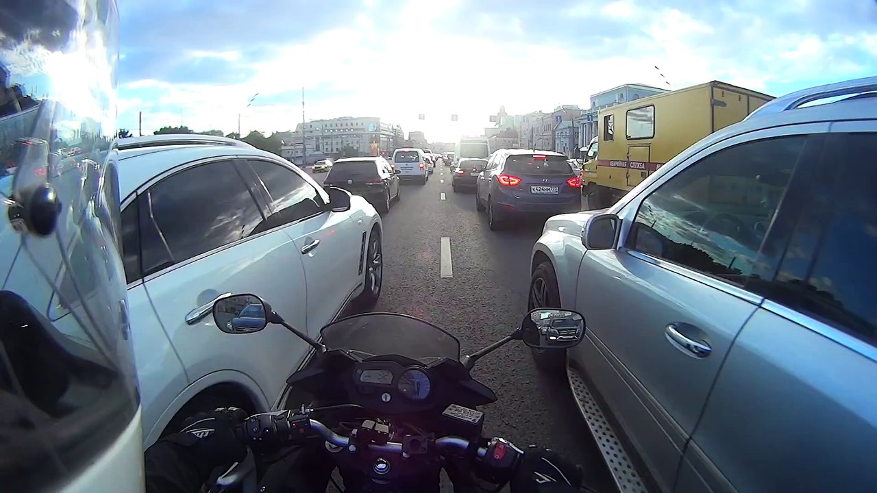 Ce motard fait passer une clope entre deux voitures... Sympa la russie !