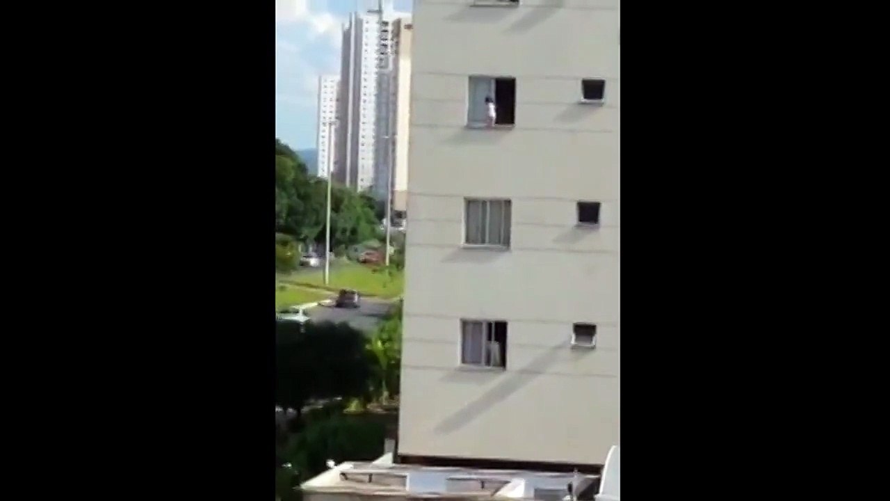 Baby walks along ledge of high rise window