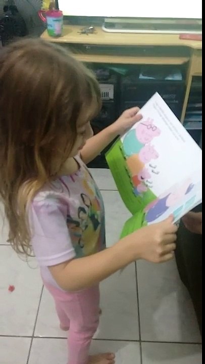 Rafaela lendo o livro da peppa pig