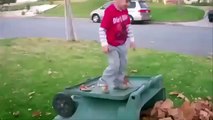 A kid falling over in a pile of leaves