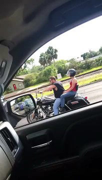 Un homme en voiture roule sur une moto.