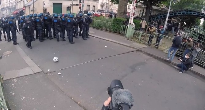Un CRS tire dans un ballon de foot en direction d'un journaliste