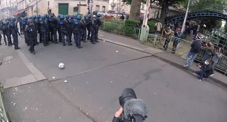 Un CRS tire dans un ballon de foot en direction d'un journaliste