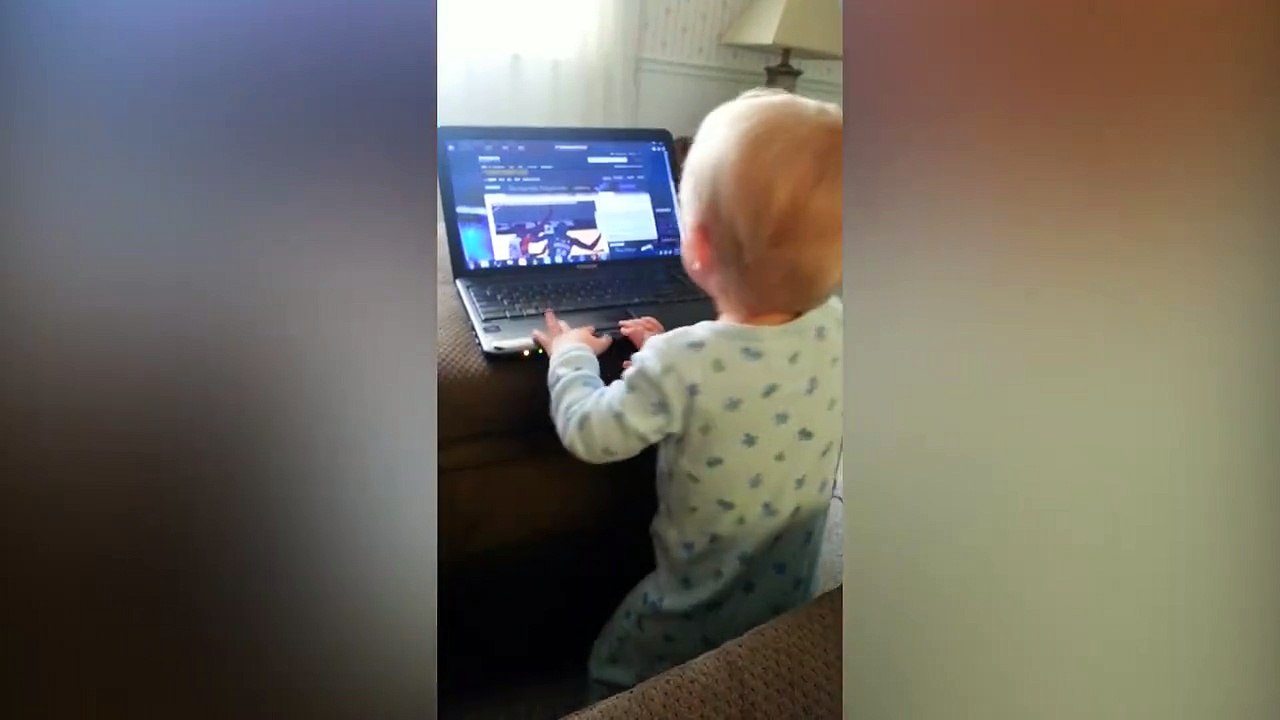 Un petit bébé joue avec un Laptop