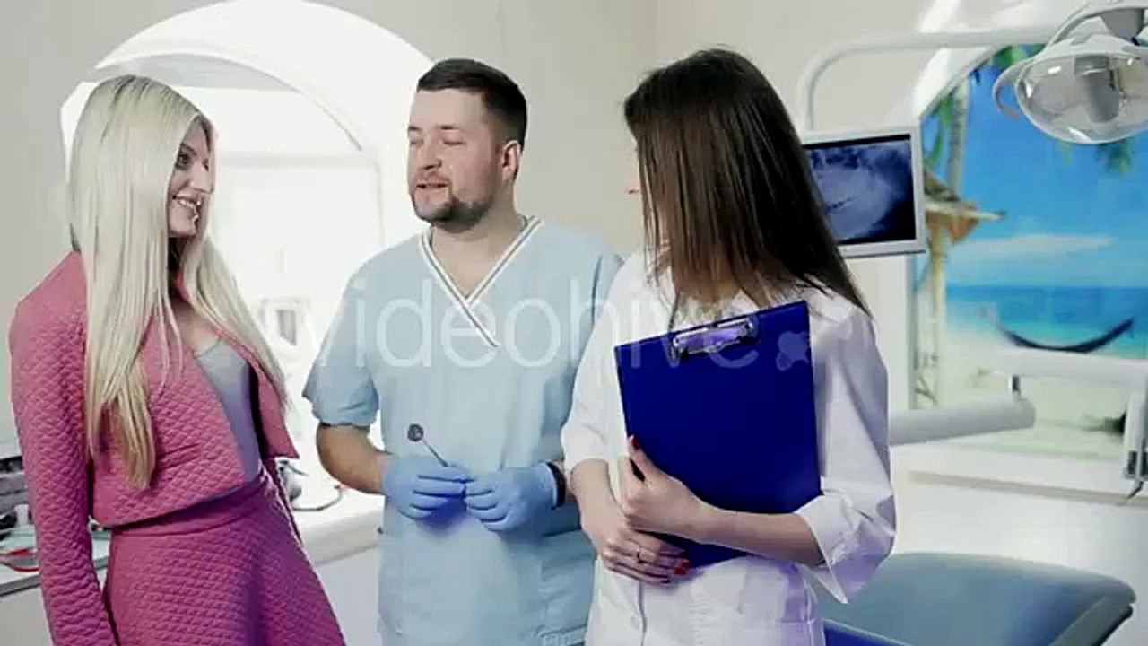 Handsome Doctor and a Patient Dentist With an Assistant Standing