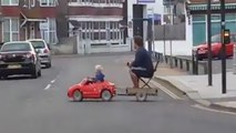 Au volant de sa mini-voiture, le petit garçon conduit son père à la maison