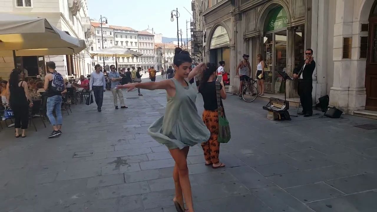 Une femme accompagne un musicien de rue en dansant