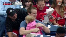 Ce spectateur attrape une balle de baseball tout en tenant sa fille et de la nourriture dans les bras