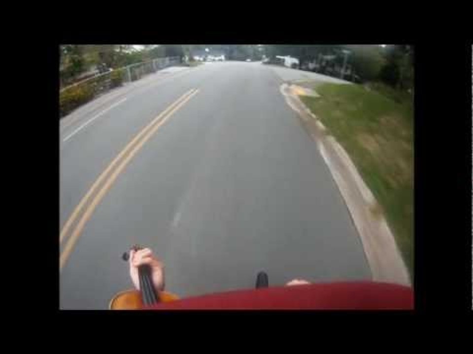 Man Rides Bike and Plays Violin at the Same Time