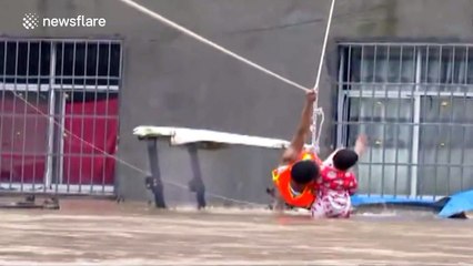 Firefighter helps child to cross flooded street