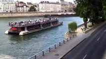 Sur la Seine, un bateau bus à l'arrêt pour laisser passer une péniche XXL