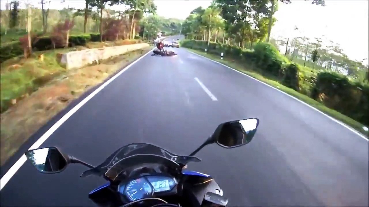 Un motard à le réflexe de se coucher pour éviter une voiture