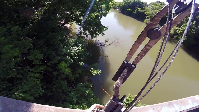 Elle peche à l'arc depuis un pont et attrape un gros poisson