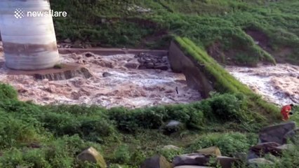 Man balances on two rocks after getting caught in fast-flowing floodwater