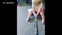 Toddler sits on a vacuum while mother cleans