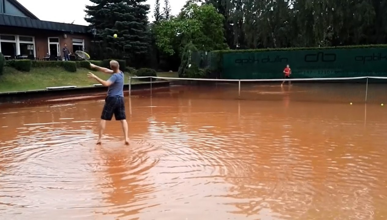 Deux hommes jouent sur un terrain de tennis inonder.