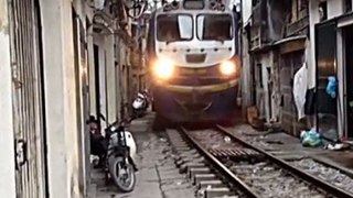 Train travels through narrow gap inbetween houses in Vietnam
