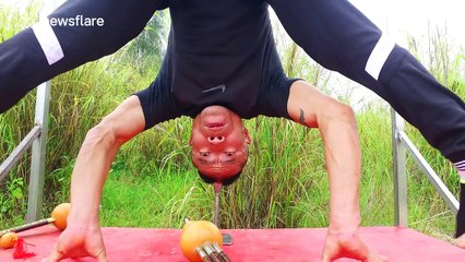 Man does a head stand on a steel pipe and plays the flute