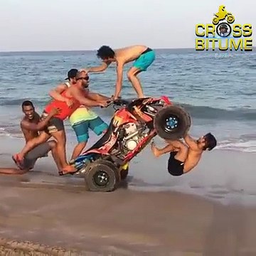 Des amis s'amusent dangereusement avec un quad sur la plage.