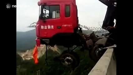 Lorry hangs off the edge of a bridge, facing a 100 metre drop