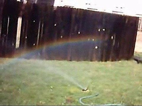 Cette femme râle contre un arc en ciel sur un arrosage automatique