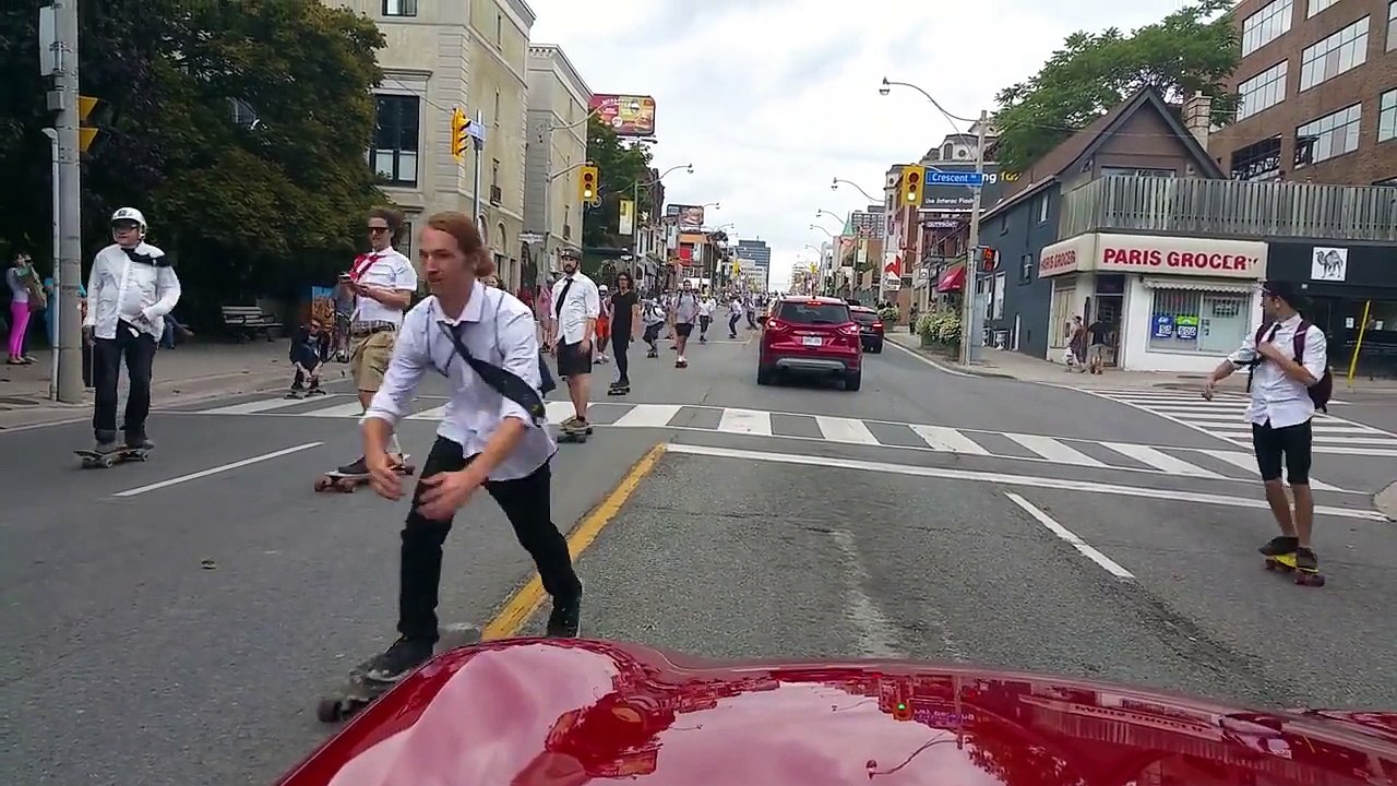 Un automobiliste entouré de centaines de skateurs au milieu de la route