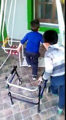 Un enfant aide son copain handicapé à s'installer sur la balançoire pour jouer avec lui...