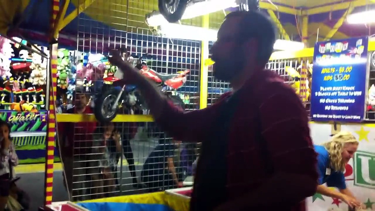 Ce mec gagne une mini moto à un jeu de fête foraine !