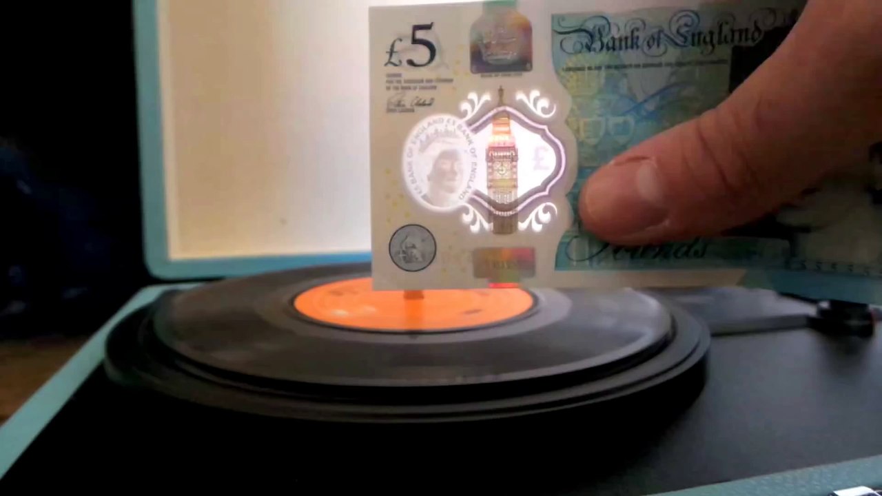 Le billet de 5 Livres anglaise fait de la musique sur une platine vinyle