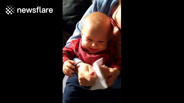 Cute baby laughs hysterically at some paper