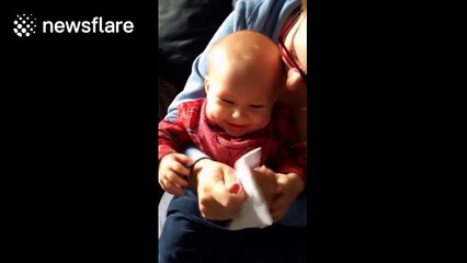 Cute baby laughs hysterically at some paper