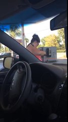 Woman bathes with squeegee at gas station