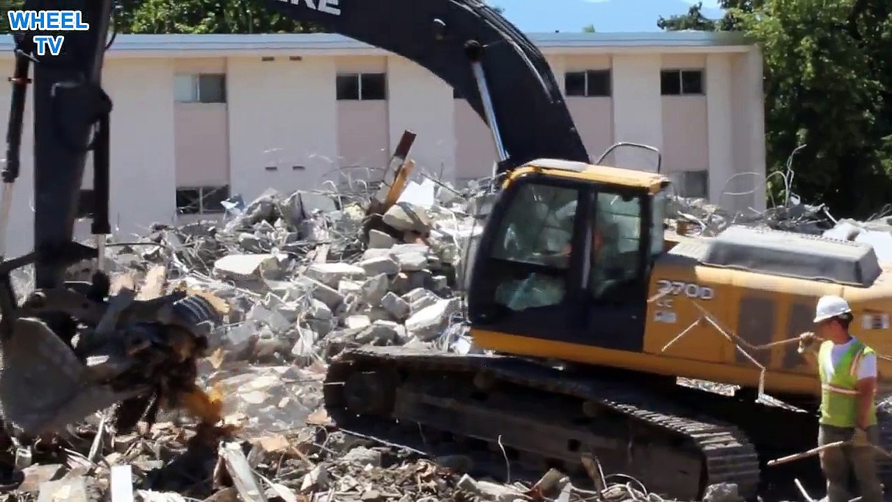Deere 270D Excavator moving lots of debris from torn down dorm buildings on a college campus