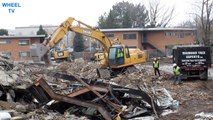 Deere and 2 CAT Excavators sifting through debris from some torn down dorms on a college campus