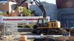 Deere 200D excavator loading asphalt and dirt into a 20 ton big rig dump truck on a construction site
