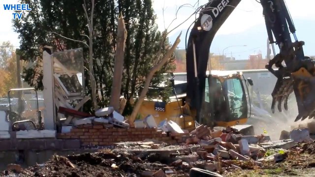 Deere 250G Excavator moving debris from a torn down building construction site