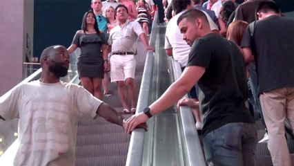 Il caresse la main des gens sur un escalator, et leurs réactions sont justes énormes !