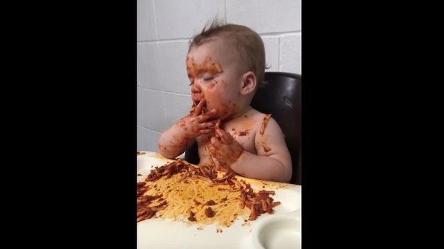 Un bébé fatigué mange des pâtes à la bolognaise