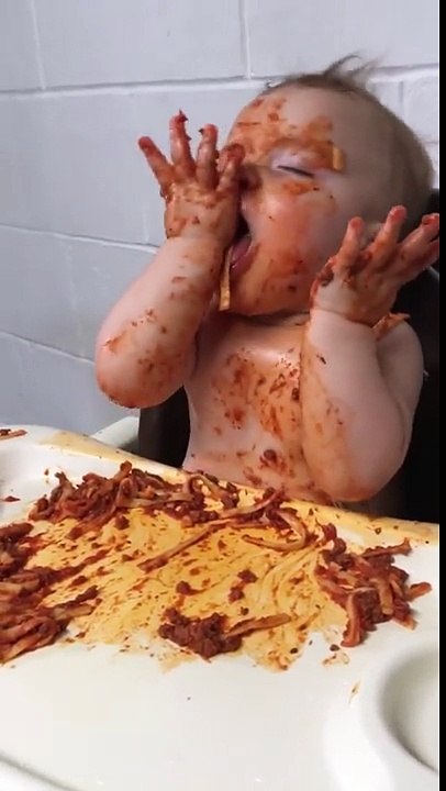 Un bébé fatigué mange des pâtes à la bolognaise