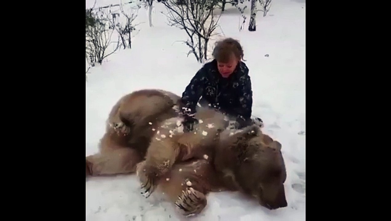 Elle fait un câ à un gros nounours dans la neige, c est adorable.