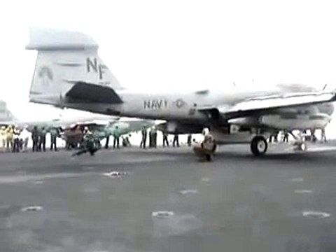 Un soldat emporté par le souffle d'un réacteur d'avion au décollage sur un porte-avion