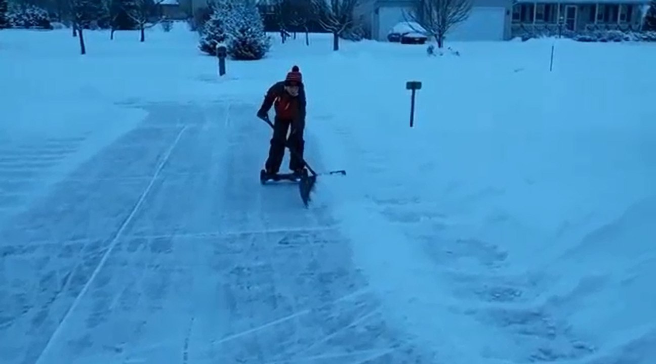 Un enfant déneige une allée avec un hoverboard.