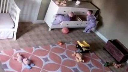 Un enfant aide son frère jumeau à se dégager d'une commode