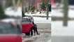 Une jeune femme se fait aider par son père pour grimper dans sa voiture stationnée dans une allée verglacée