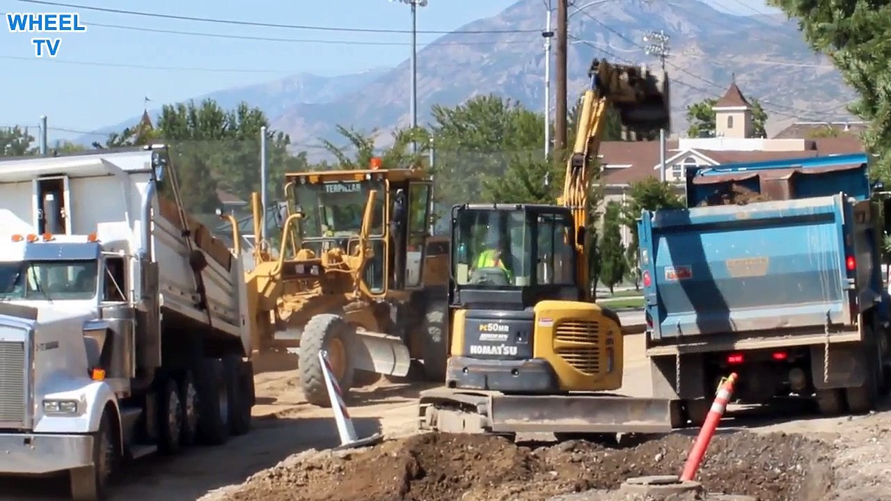 Komatsu PC50MR Mini excavator loading a blue dump truck with dirt from a road construction site