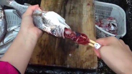 Elle vide les poissons avec deux baguettes