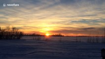 Stunning sunset over wind-swept, snow-covered field
