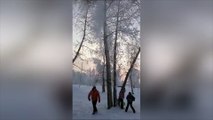 Le père tape dans cet arbre et la neige tombe sur ses enfants