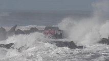 Une voiture sur une jetée au milieu des vagues